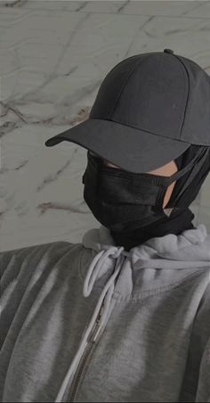 a man wearing a black hat with a face mask on his head and grey hoodie