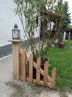 a wooden fence with a potted plant next to it and a lantern on top