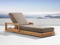 an outdoor chaise lounge chair sitting on top of a white floor next to the ocean