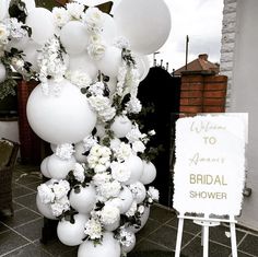 white balloons and flowers are on display in front of a sign for the bridal shower