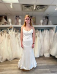 a woman is standing in front of some wedding dresses