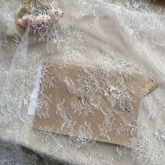 a piece of cloth with white lace on it sitting on top of a table next to flowers