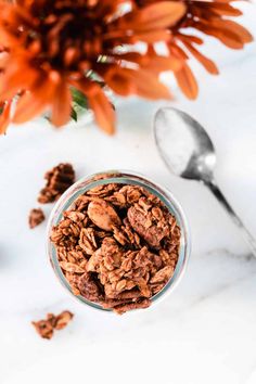 a glass bowl filled with granola next to an orange flower