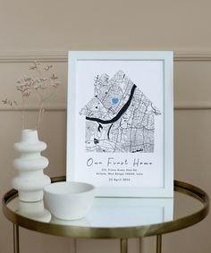 a white vase sitting on top of a table next to a framed map and bowl