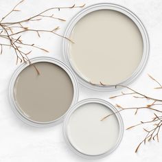 three white paint cans sitting on top of a table next to some dry grass and twig