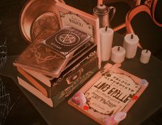 a table topped with lots of books next to candles and other items on top of it