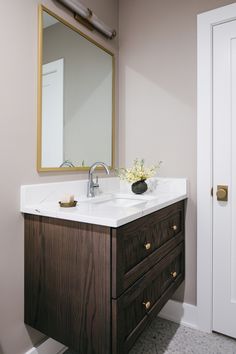 a bathroom sink with a mirror above it and a vase on the counter next to it