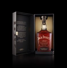 a bottle of jack daniels whiskey sitting in a black box on a dark surface with its lid open