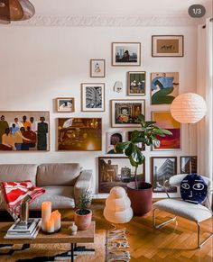 a living room filled with lots of pictures on the wall and plants in vases