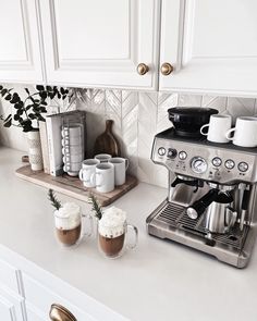 a coffee maker sitting on top of a kitchen counter next to cups and mugs