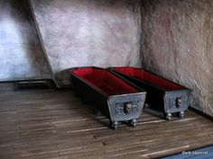 two metal containers sitting on top of a wooden floor next to a wall with stone walls