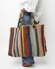 a person holding a multicolored bag in front of their back with one hand