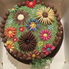 there is a cake decorated with flowers and chocolates on the top, in a box