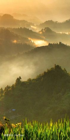 the mountains are covered in fog and low lying clouds as the sun rises over them