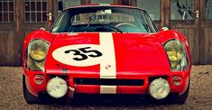 a red sports car parked in front of a wooden building with the number 35 on it