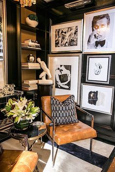 a living room filled with lots of pictures and art on the wall next to a chair