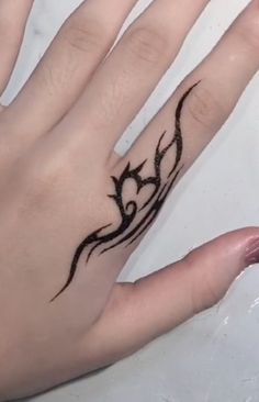 a woman's hand with a black tattoo on it and a ring in the middle