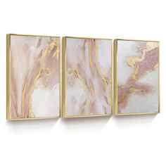 three gold and white paintings hanging on the wall in front of a white background, each with