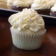 two cupcakes with white frosting on top are sitting side by side in front of each other