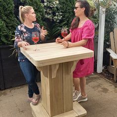 two women standing at a table with wine glasses