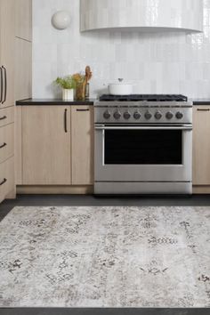 a kitchen with an area rug on the floor and stove top oven in the middle