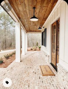 the front porch is lined with white pillars and brick walkways that lead up to two large windows