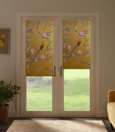 a living room with sliding glass doors that have birds on them and flowers in the window