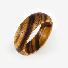 The Round Band ring handmade from solid zebrawood. Made to your ring size when you order, other woods available upon request. The round band gives this ring design a classic feel while allowing the unique woodgrain and the texture of the zebrawood to become the main focus (also called zebrano wood). Though understated, these wood rings are thoughtfully made in a slow hands-on process, no lathe, no CNC machining. I think the care that goes into making these by hand can be felt, even if it isn't apparent at first glance. What you see pictured are pieces I have made and represent what you are ordering. However, your ring will be unique to you and may vary slightly in color and grain pattern. Wood is a natural material, each piece is different and should be enjoyed for its individuality. ◆ Con Handmade Round Wooden Jewelry, Minimalist Brown Rings For Gifts, Round Brown Wooden Jewelry, Brown Round Wooden Jewelry, Mens Wood Rings, Slow Hands, Wooden Rings Engagement, Wooden Wedding Ring, Bentwood Rings