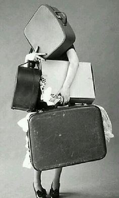 a woman is carrying two suitcases on her back while wearing a dress and heels