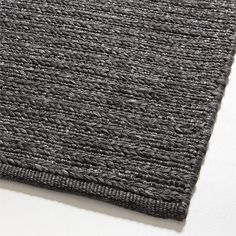 a close up view of the textured fabric on an area rug that is dark gray