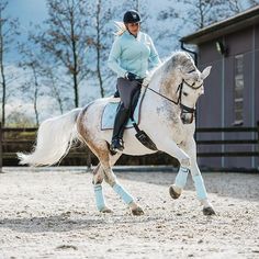 a woman riding on the back of a white horse