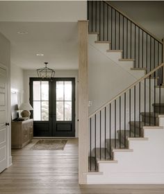 an empty entryway with stairs leading to the front door and another room in the background