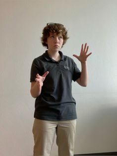 a person standing in front of a wall with their hands up and one hand out