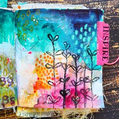 an altered book with flowers on it and the words inspire written in pink, green, blue