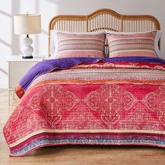 a bed with pink and purple bedspread on top of it