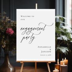 a welcome sign for an engaged party with candles and flowers on the table next to it