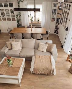 a living room filled with furniture next to a dining table and bookshelf on top of a hard wood floor