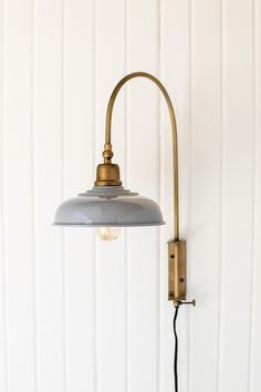 a lamp that is on the wall next to a white wall with a black cord