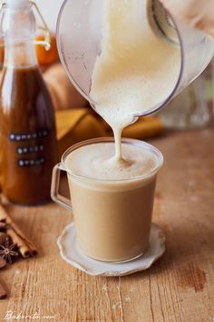 someone pouring something into a cup on top of a wooden table