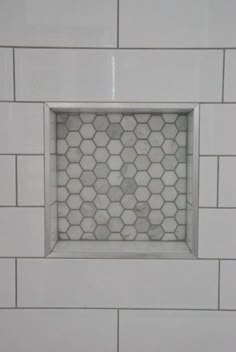 a white tiled wall with a small window in the middle that looks like hexagonal tiles