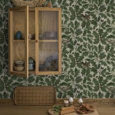 a wooden cabinet sitting on top of a table next to a wallpapered wall