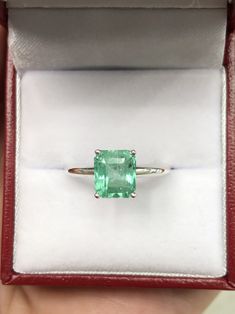 an emerald ring in a red velvet box