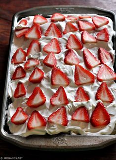 a pan filled with strawberries and cream on top of a wooden table