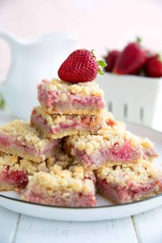 strawberry crumb bars stacked on top of each other with strawberries in the background