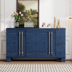 a blue sideboard with gold handles in a white walled living room, next to a painting on the wall