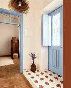 a blue door and window in a room with tile flooring next to a potted plant