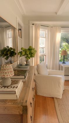 a living room filled with furniture next to a window covered in white curtained drapes