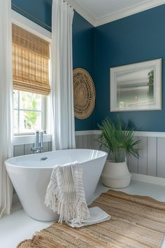 a white bath tub sitting in a bathroom next to a window with curtains on it