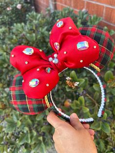 a hand is holding up a red minnie mouse ears headband with sequins