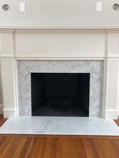 a fireplace with white marble surround and wood flooring